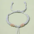 Detail von handgewebtem Armband mit rosa Blumenakzenten und verstellbarem Gleitknoten - Silbergrau