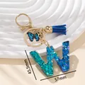 Portachiavi lettera W in resina blu con ciondolo a farfalla e nappa su sfondo bianco - Blu W