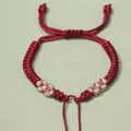 Detail von handgeflochtenem bordeauxrotem Armband mit rosa Zierknoten-Muster - Weinrot
