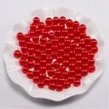 Macrodetail van rode ABS-parels met gaatjes in een witte schaal voor DIY-sieraden - Rood