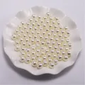 Detailweergave van witte ronde imitatieparels met voorgeboorde gaten in een keramische schaal - Broken Wit