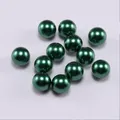 Macro shot of 11 smooth emerald green round faux pearl beads for jewelry making - Dark Green