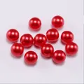 Close-up of vibrant red round faux pearls with glossy finish for DIY jewelry making - Red