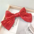 Dettaglio di un fermaglio per capelli con fiocco in raso rosso su fondo in legno - Rosso Vero