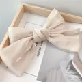 Vue macro d'une barrette noeud en satin doré champagne avec texture nacrée élégante - Ivoire
