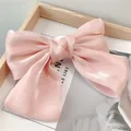 Détail d'une pince à cheveux à double nœud en satin rose sur une carte blanche - Rose Clair
