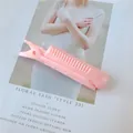 Pink hair root volumizing clip with comb teeth detail on a stylish magazine background - Pink