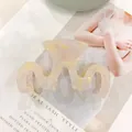 Makro-Detail der M-förmigen Haarklammer mit rosa Marmor-Acetat-Muster auf Magazin - Gelbes Marmormuster
