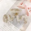 Gros plan sur la pince à cheveux ondulée en acétate ivoire avec texture marbrée - Motif Marbre Ivoire