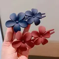 Matte floral hair clips in navy blue and dark red held in hand for hairstyle - Red