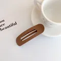 Fermaglio per capelli marrone opaco oversize traforato su sfondo bianco stile minimalista - Stile Ambra Caffè
