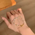 Detailed view of 18k gold plated flower bracelet with zircons worn on a lady's hand - Gold
