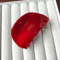 Pince à cheveux rouge brillant en acétate avec texte doré sur support en velours blanc - Rouge