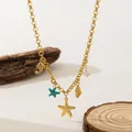 Collier doré avec pendentifs étoile de mer et coquillage sur fond bois rustique - Collier Perle Artificielle Étoile de Mer Dauphin (H1283) / Or