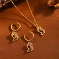 Detailansicht eines goldenen Delfin-Schmucksets mit Pavé-Halskette und Creolen-Ohrringen. - Doppelter Delfin / Halsketten- und Ohrring-Set / Gold