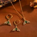 Detailansicht von vergoldetem Meerjungfrauenschwanz-Schmuckset mit grünen Kristallen - Fischschwanz mit Einzelnem Grünem Strass / Halsketten- und Ohrring-Set / Gold