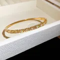 Gros plan d'un bracelet en acier doré avec des zircons brillants et des gravures - Style 16 Gravé Étoile / Or