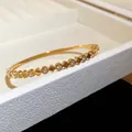 Gros plan d'un jonc en acier doré orné de zircons étincelants en forme de cœur - Style 15 Cœur et Zirconia Rond / Or