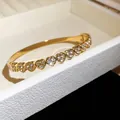 Gros plan sur les maillons en forme de cœur sertis de zircones sur un jonc doré. - Style 14 Chaîne Cœur / Or