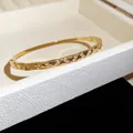 Gros plan d'un jonc en acier inoxydable doré avec incrustations de zircons - Style 13 Facettes Irrégulières / Or