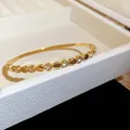 Vue rapprochée d'un bracelet jonc en acier doré avec des cœurs et zircons étincelants - Style 11 Cœur Évidé / Or