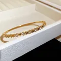 Gros plan d'un bracelet jonc en acier doré avec des cœurs et zircons scintillants - Style 6 Cœur 3D / Or