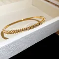 Détail d'un jonc en acier inoxydable doré avec motif cœur et pierres en zircone étincelantes - Style 4 Cœur Zirconia / Or