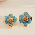 Close-up view of elegant blue enamel flower jewelry with golden metal petal textures - Earrings / Blue