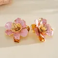 Macro detail view of elegant pink enamel flower ring with pleated gold metal finish - Earrings / Pink