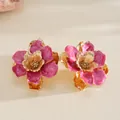 Détail d'une bague en métal doré avec un motif de fleur en émail rose pour femmes - Boucles d'oreilles / Rose rouge