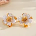 Vue détaillée de deux bagues fleurs dorées avec pétales en émail nacré et froissé - Boucles d'oreilles / Blanc