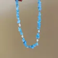 Dettaglio di una collana curativa in pietra blu con eleganti perle bianche da donna - Blu