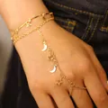 Detail of gold-plated hand chain with star and moon tassel charms on a double-layer bracelet - Star and Moon (1923) / Gold