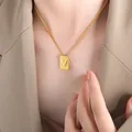 Elegant gold square pendant necklace with letter V worn by a model in a khaki blazer - Letter V Style (P1506-V)
