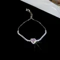 Detalle macro de una pulsera de circonita rosa brillante en forma de corazón sobre fondo negro - Estilo 16# Plateado Rosa Corazón