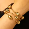 Detailansicht eines eleganten dreiteiligen goldfarbenen elastischen Perlenarmbands am Handgelenk - Goldperlen Dünnes Rohr Stapelbarer Stil (2120)
