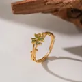 Close-up of golden adjustable ring with green heart-shaped gems in flower design - Olive Green Plum Blossom (F1267)