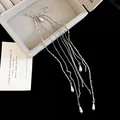 Detailed macro shot of a silver safety pin brooch with elegant long metal chain tassels. - Tassel Pin (HP1008) / Silver