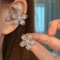 Élégantes boucles d'oreilles fleur en zircon portées à l'oreille et tenues à la main. - Manchettes d'oreilles / Une Paire / Argent