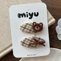 Détail de 2 barrettes à carreaux avec ours brodé et nœud en velours marron sur carte - Style Ours Brun