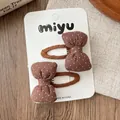 Dettaglio di fermagli per capelli a fiocco marrone a pois su uno sfondo di legno - Fiocco In Tessuto A Pois Caffè