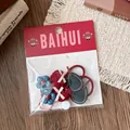 Dettaglio di elastici per capelli rossi con fiori e fiocchi in confezione su tavolo - Stile Fiore Pera