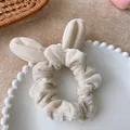 Dettaglio di un elastico in velluto beige con orecchie di coniglio su vassoio bianco - Beige