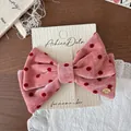 Pink velvet hair clip with red polka dots and a golden metal brand name plate - Large Bow Clip
