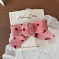 Pink polka dot corduroy bow hair clip on a branded cream display card with gold logo - Fishtail Bow Clip