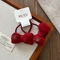 Détail de nœuds en velours rouge avec broderie d'étoiles dorées pour filles sur support - Chouchou Nœud Brodé
