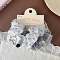 Detail of floral and plaid scrunchie with cute bear label and buttons on display card - Blue Floral