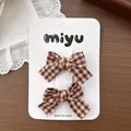 Détail de pinces à cheveux à nœuds à carreaux marron et blanc sur carte de présentation - Nœud à Carreaux