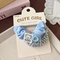 Dettaglio di scrunchies in tessuto a quadretti blu con patch a forma di orsetto - Stile Bottone Orso Blu