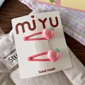 Detailed macro view of two pink handmade peach hair clips on a white display card - Peach